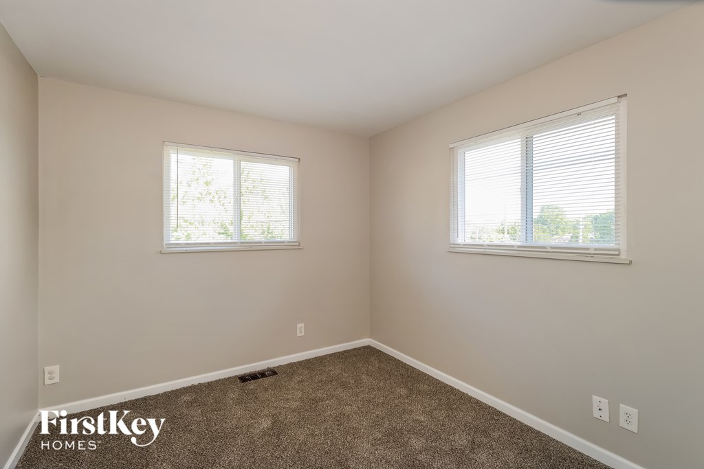 A room with two windows and a carpeted floor.