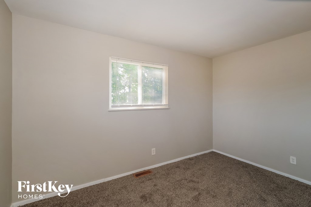 A room with a carpeted floor and a window with blinds.