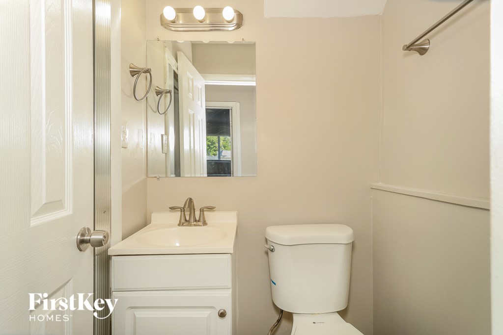 A white toilet in a bathroom with a mirror above the sink.