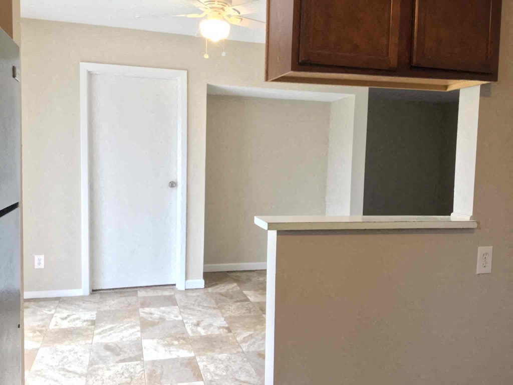A kitchen area with a refrigerator, a door, and a countertop.