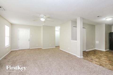 A spacious room with a ceiling fan and lighting fixtures.