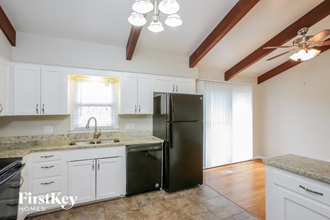 a kitchen with white cabinets and a black refrigerator