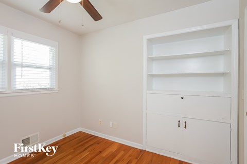 a bedroom with white walls and shelves and a ceiling fan