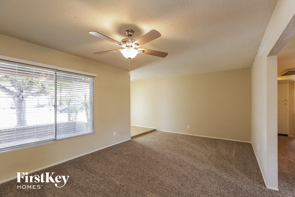 an empty living room with a ceiling fan and a large window