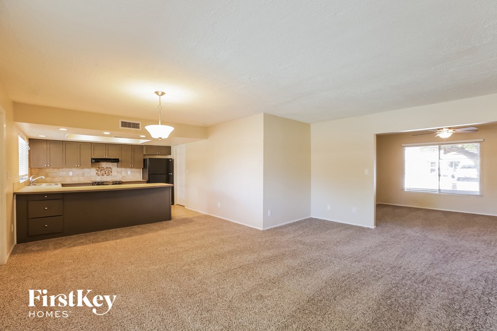 an empty living room and kitchen with a counter top and a window