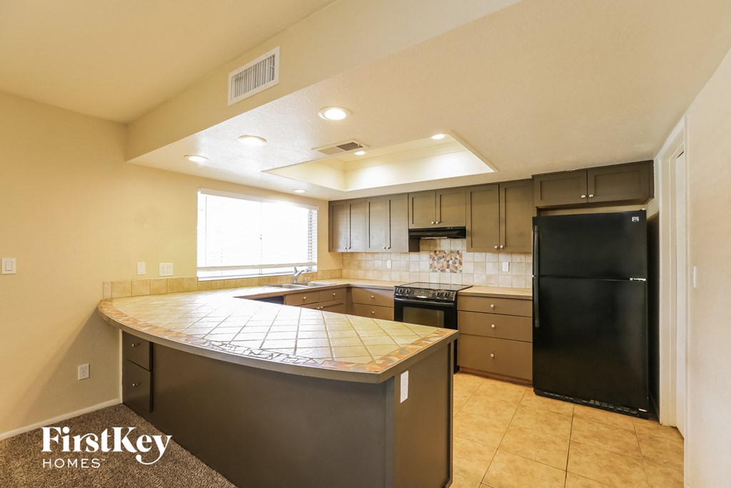 a kitchen with a large counter top and a black refrigerator