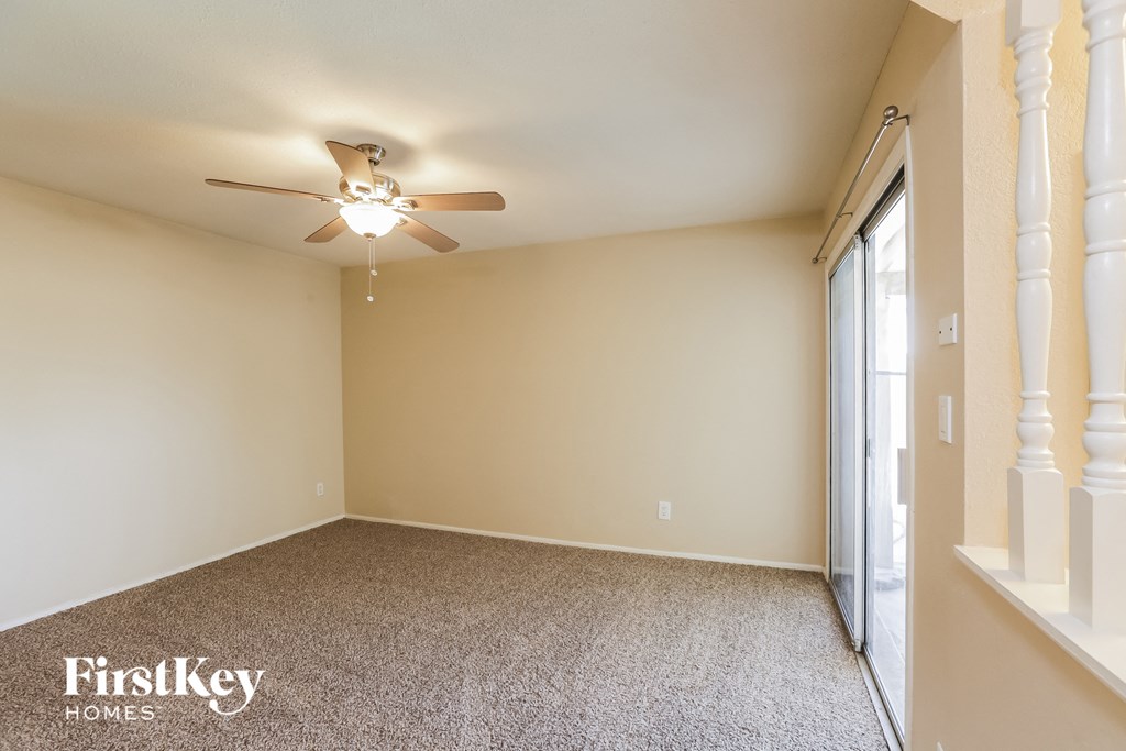 a empty living room with a ceiling fan and a window