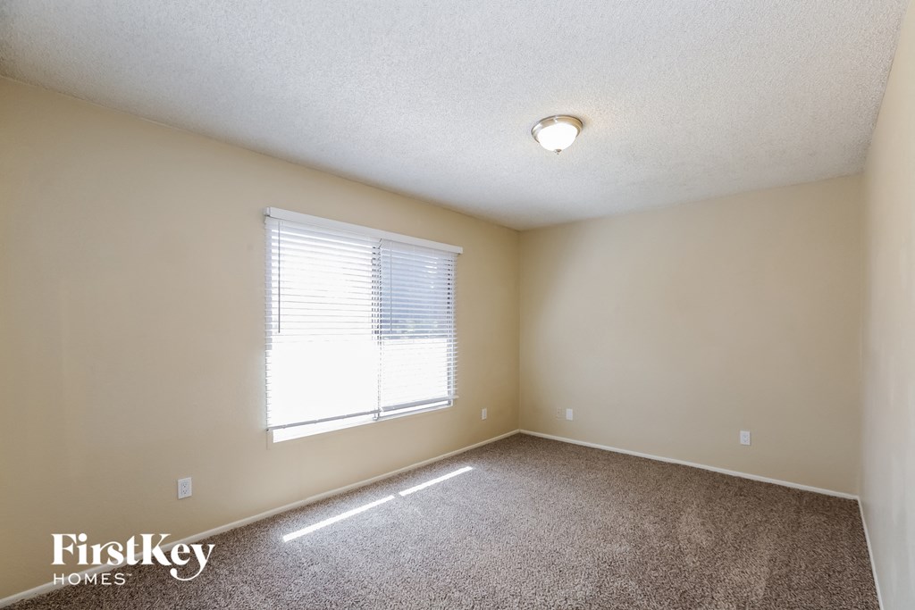 an empty room with a window and a carpeted floor