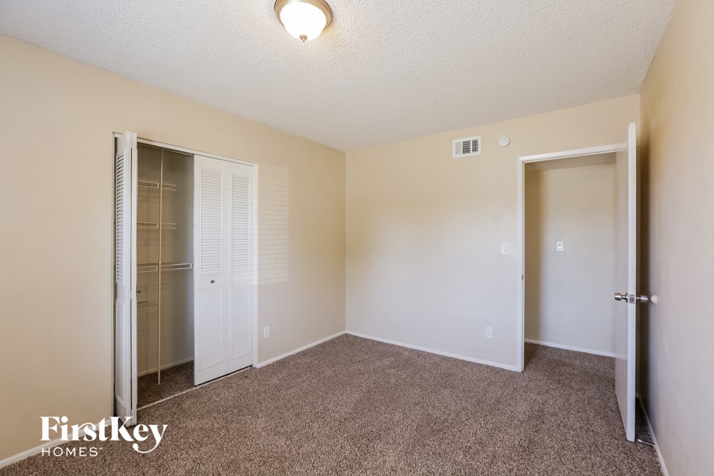 the living room of an apartment with carpet and a closet