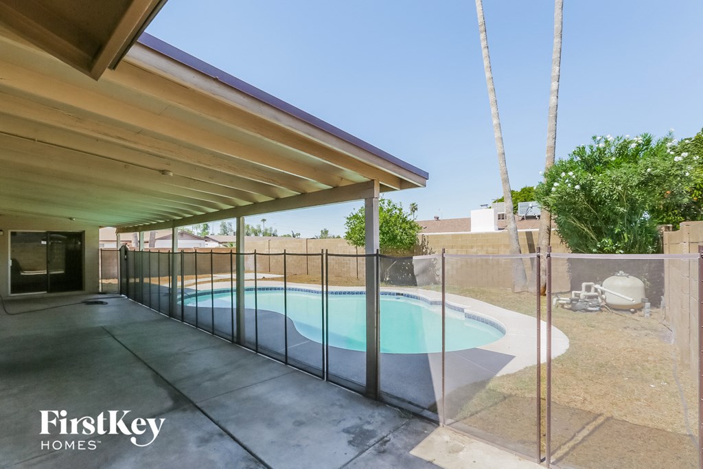 the pool is in the backyard of a house with a glass fence