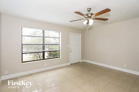 A room with a ceiling fan and a window with blinds.