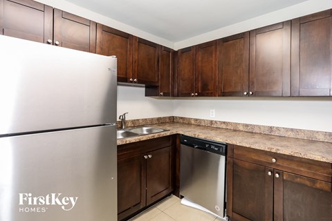 A kitchen with a stainless steel refrigerator and wooden cabinets.