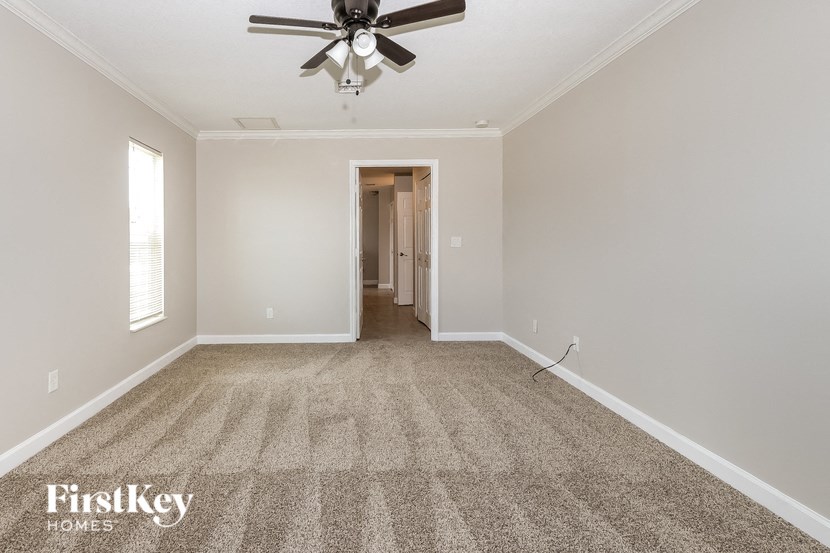 an empty living room with a ceiling fan and carpet