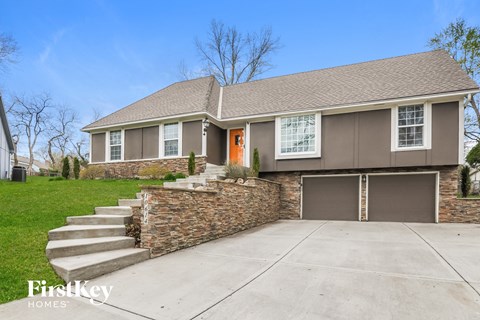 front view of a home with stairs to the driveway and a garage door