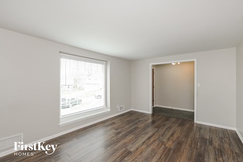 the living room of a home with wooden floors and a large window