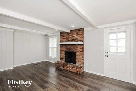 a living room with a brick fireplace and wooden floors