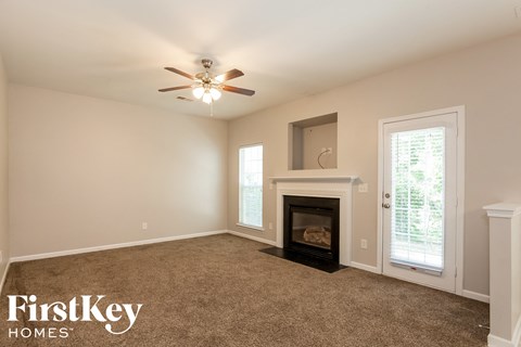 an empty living room with a fireplace and a ceiling fan