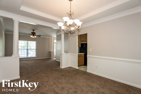 an empty dining room with a chandelier and a window