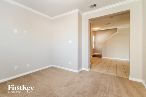 A spacious room with a carpeted floor and a stairway leading to another room.