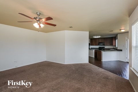 A spacious living room with a carpeted floor and a ceiling fan.
