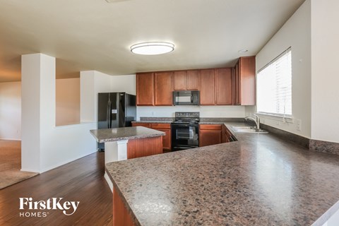 A kitchen with a granite countertop and wooden cabinets.