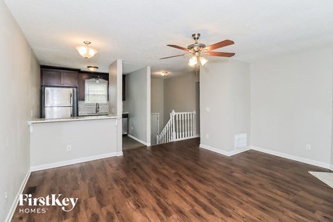 A room with a fan and wooden floors.