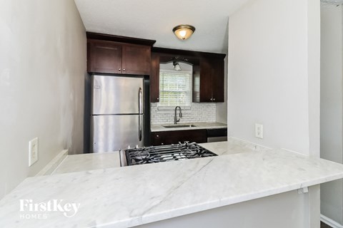 A kitchen with a marble countertop and a stainless steel refrigerator.