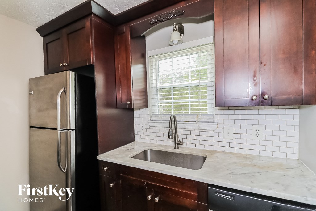 A kitchen with a refrigerator, sink and cabinets.