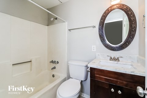 A bathroom with a toilet, sink and mirror.