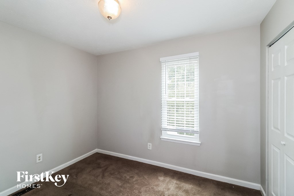 A room with a window and a carpeted floor.