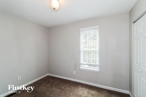 A room with a window and a carpeted floor.