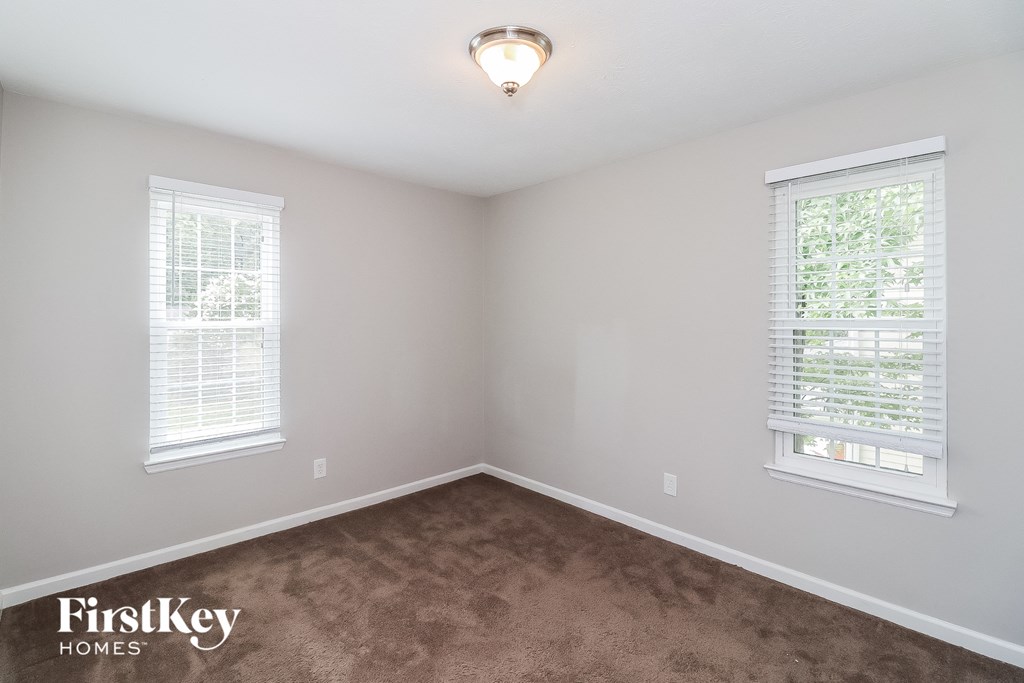 A room with two windows and a carpeted floor.