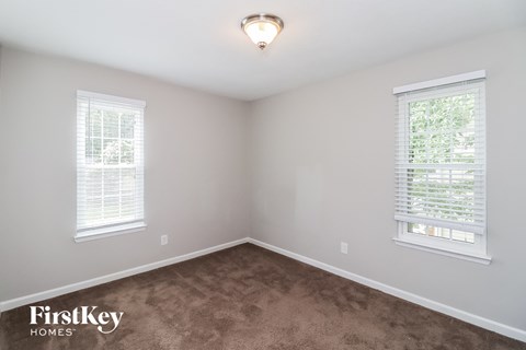 A room with two windows and a carpeted floor.