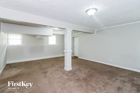 A spacious room with a carpeted floor and a column in the middle.