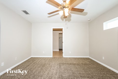a spacious living room with white walls and a ceiling fan