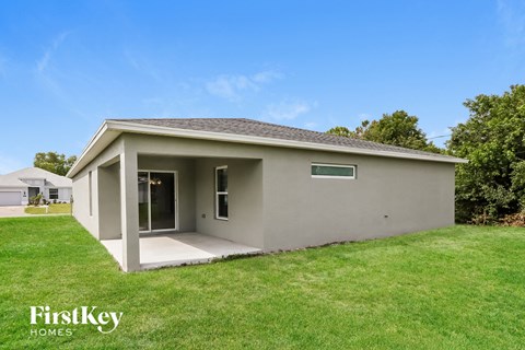 a small gray house with a lawn and a grass yard