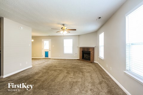 A spacious living room with a fireplace and a ceiling fan.
