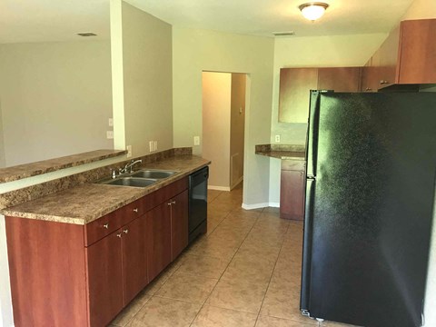A kitchen with brown cabinets and a black refrigerator.