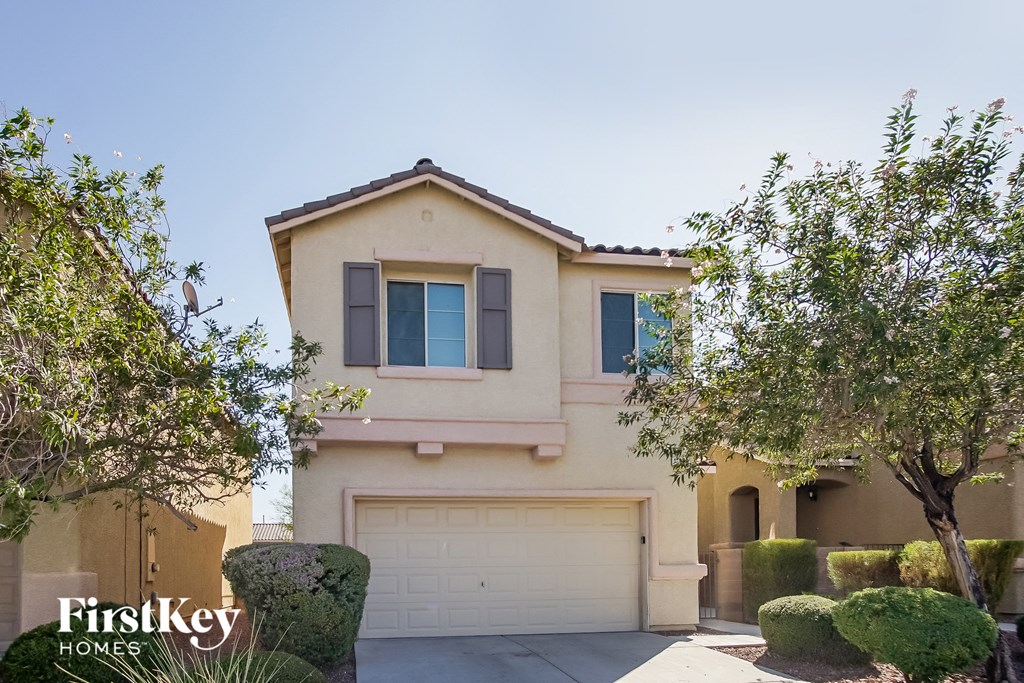 a beige house with a garage door and trees
