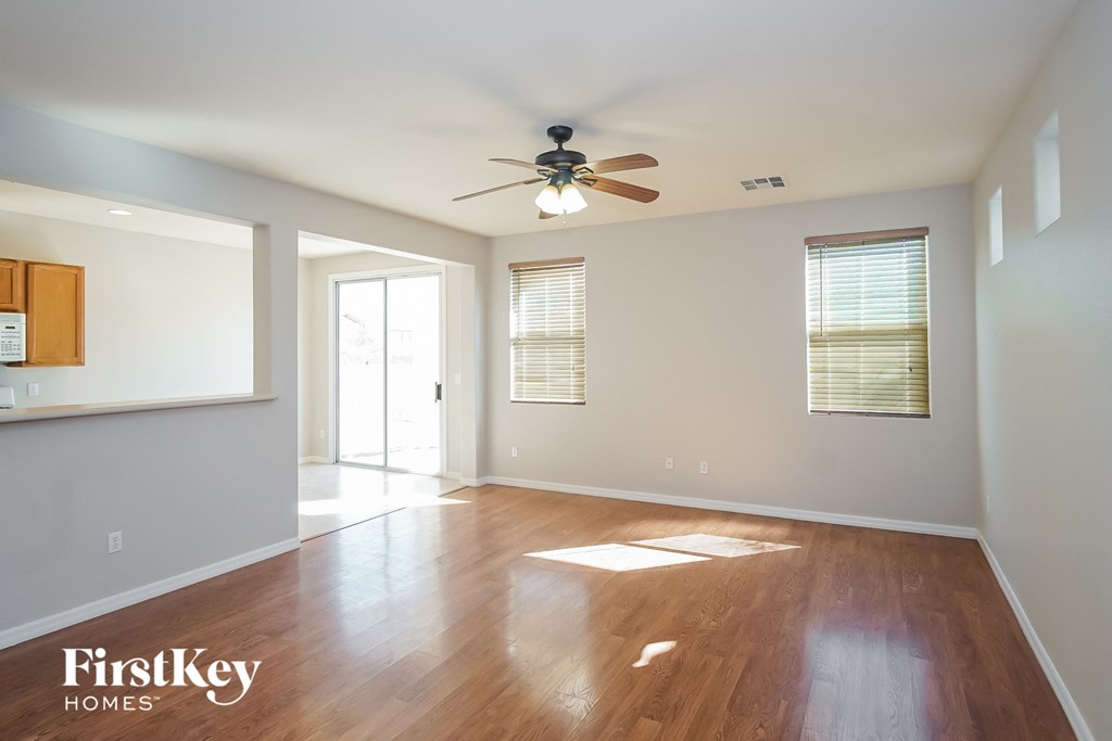 an empty living room with wood floors and a ceiling fan