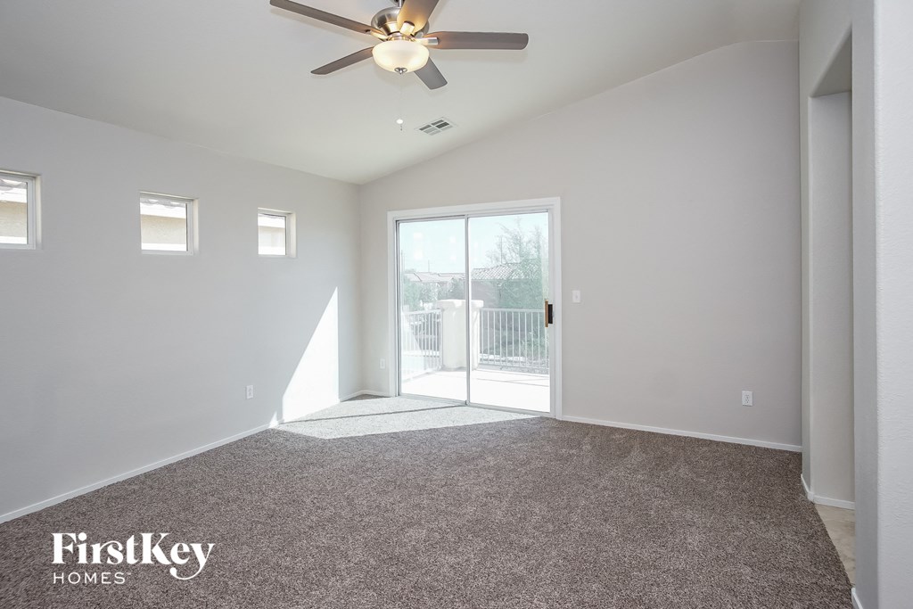 a living room with a ceiling fan and a door to a balcony