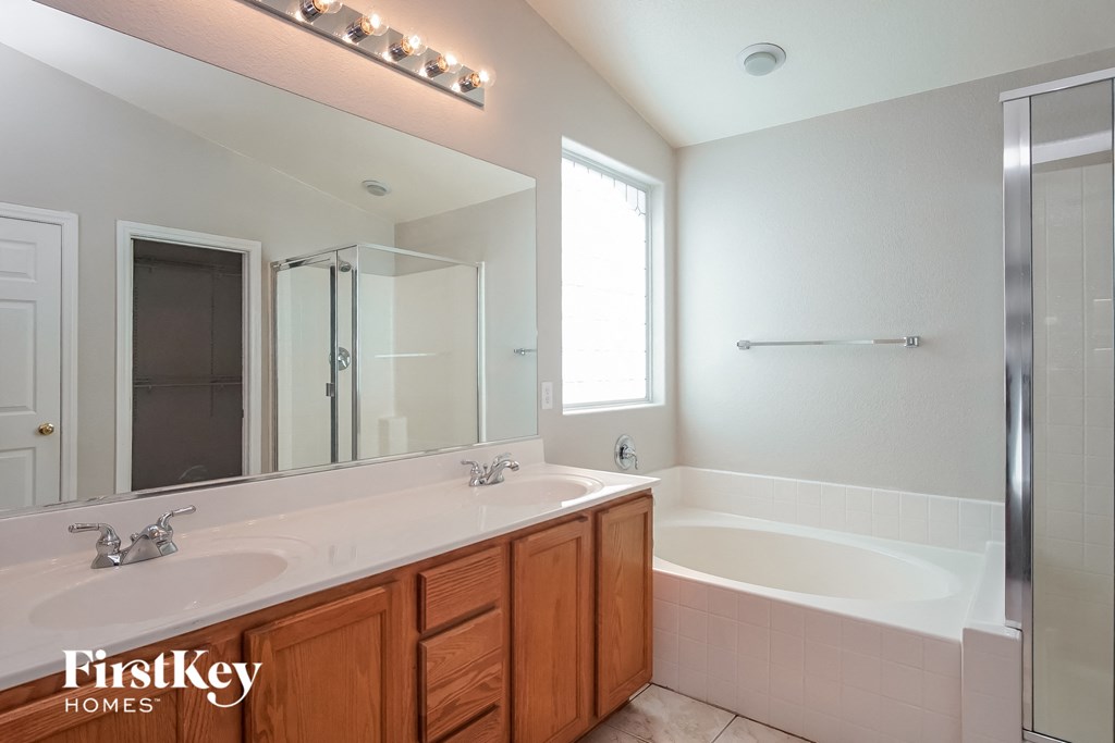 a bathroom with two sinks and a tub and a large mirror