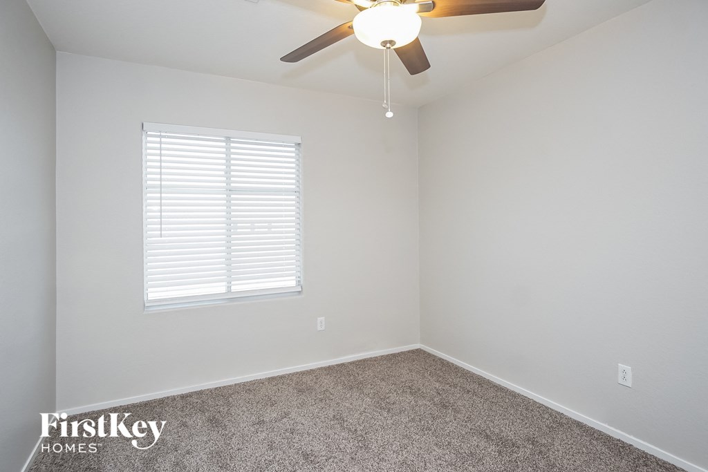 an empty room with a ceiling fan and a window