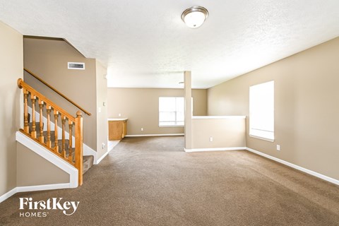 A spacious room with a staircase and a window.