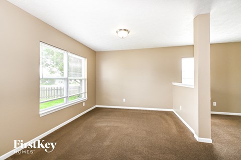 A room with a carpeted floor and a window overlooking a fence.