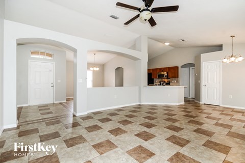 A spacious living room with a checkered floor and a ceiling fan.