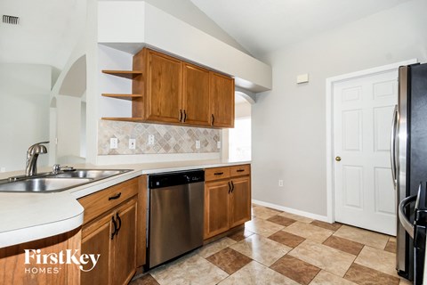 A kitchen with a checkered floor and wooden cabinets.