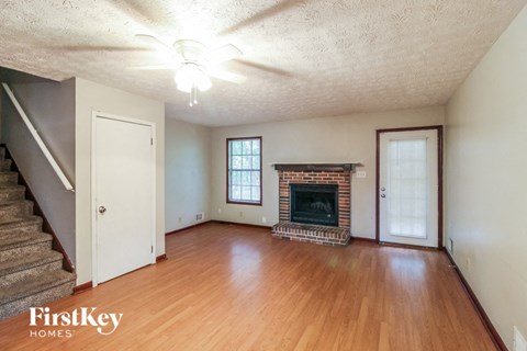 an empty living room with a fireplace and wooden floors
