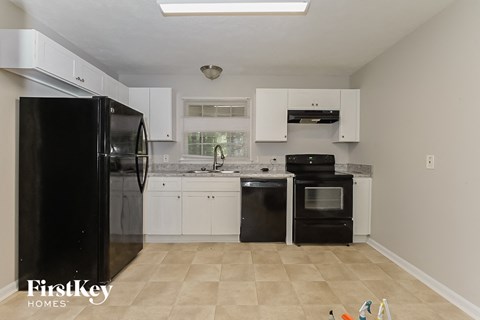 A kitchen with black appliances and white cabinets.