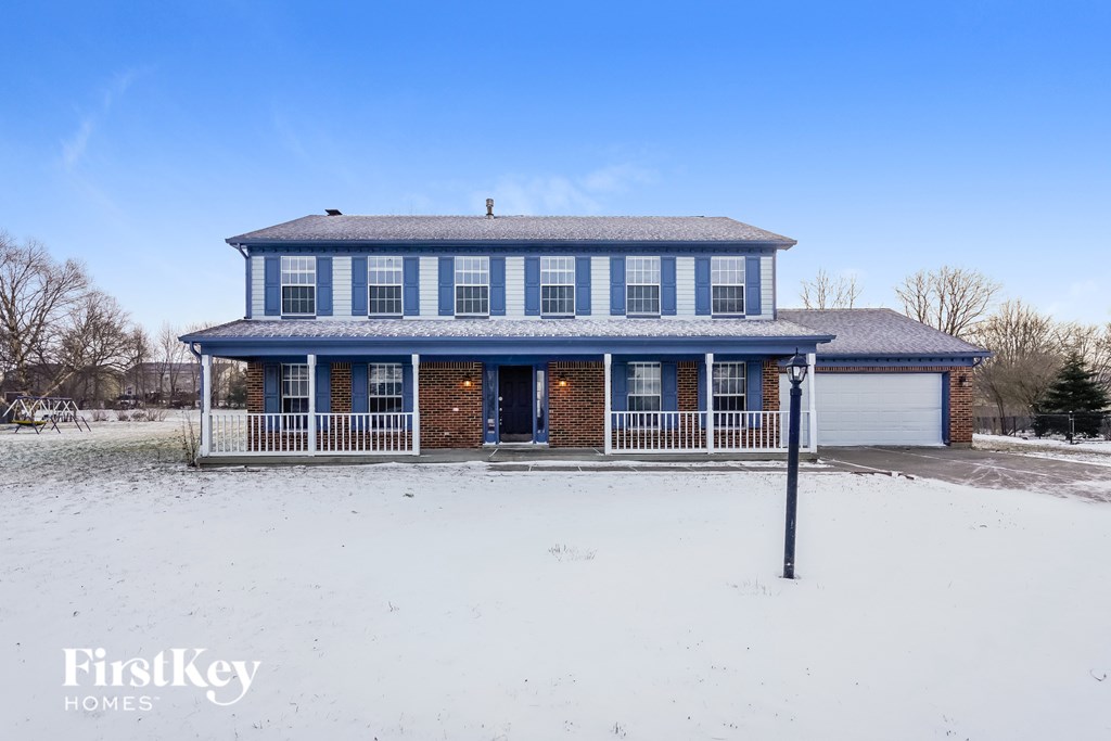 A blue and white house with a snowy landscape in front.